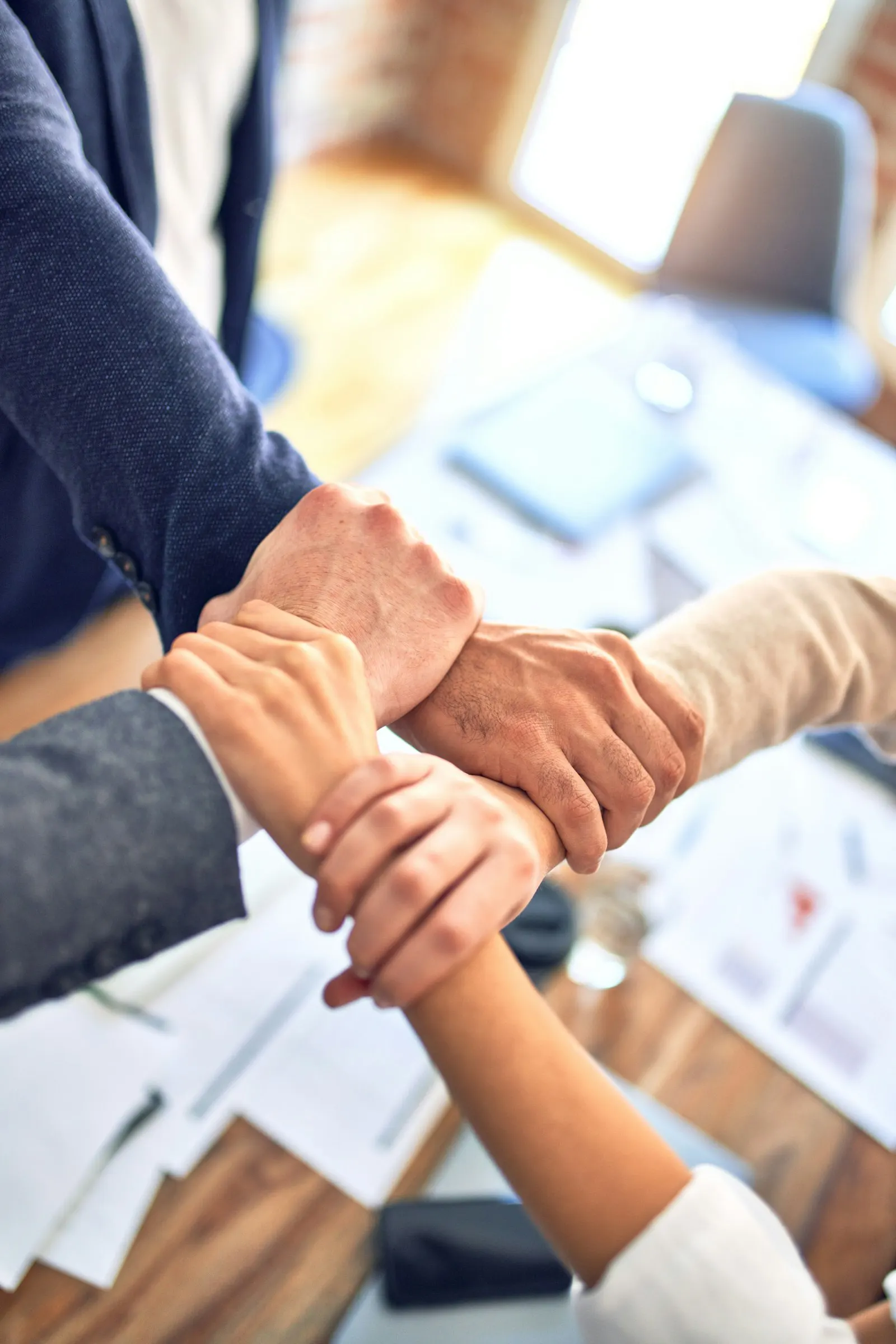 Une équipe réunie joint les mains au-dessus d'une table de travail
