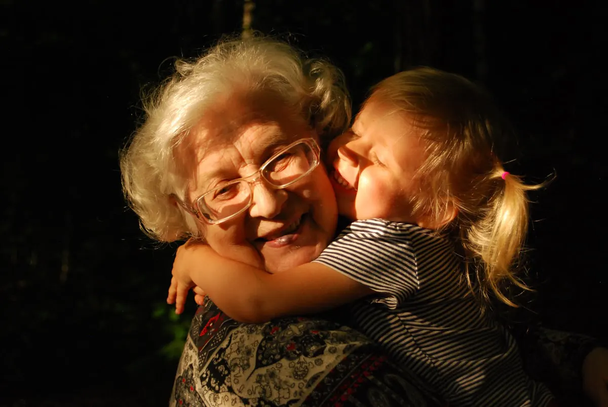 Une grand-mère souriante serrée dans les bras de sa petite-fille, dans une lumière dorée